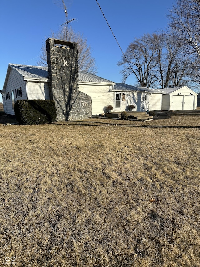 rear view of house with metal roof, a lawn, and a chimney