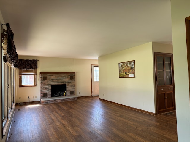 unfurnished living room featuring a fireplace, plenty of natural light, and dark wood-type flooring