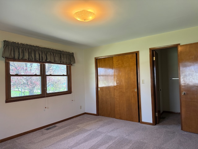 unfurnished bedroom featuring a closet and light colored carpet