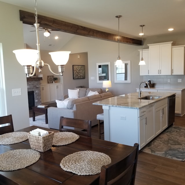 kitchen featuring pendant lighting, a brick fireplace, dark hardwood / wood-style floors, sink, and light stone counters