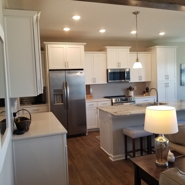 kitchen featuring white cabinets, hanging light fixtures, backsplash, and stainless steel appliances