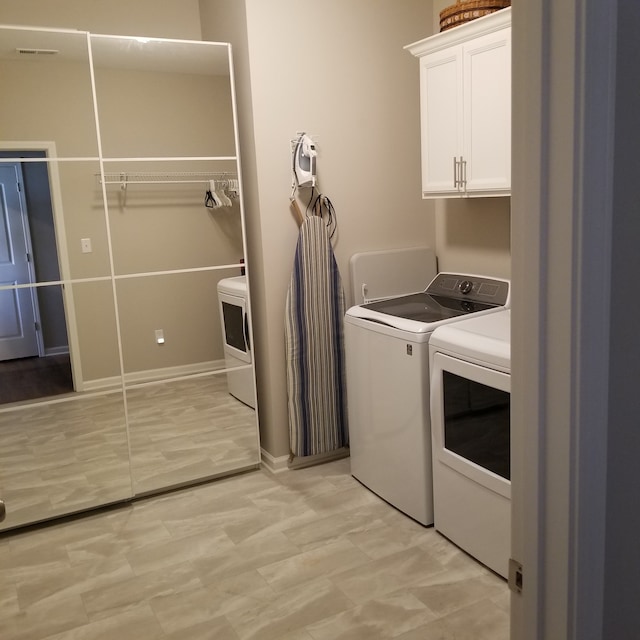 laundry room featuring cabinets, light tile floors, and washing machine and clothes dryer