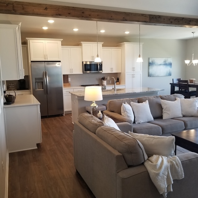 living room featuring beamed ceiling, dark hardwood / wood-style flooring, and a chandelier