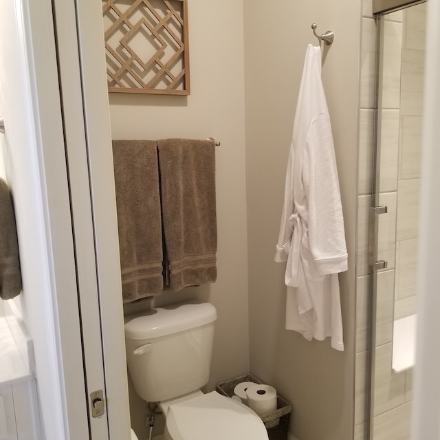 bathroom featuring a shower with shower door and toilet