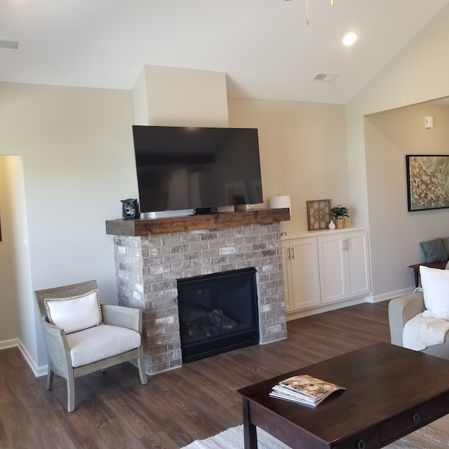 living room with dark wood-type flooring, a brick fireplace, and lofted ceiling