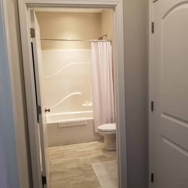 bathroom with toilet and shower / tub combo with curtain