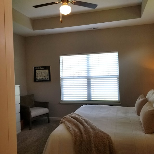 carpeted bedroom featuring ceiling fan and a raised ceiling