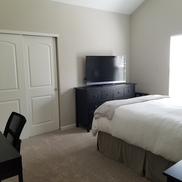 bedroom with a closet, vaulted ceiling, and light carpet