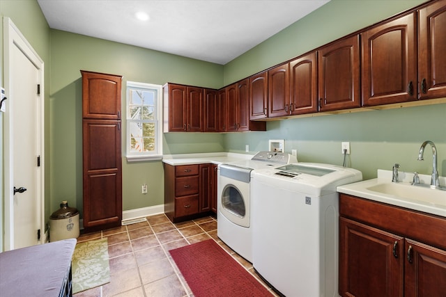 clothes washing area featuring cabinets, light tile floors, washer and clothes dryer, sink, and washer hookup