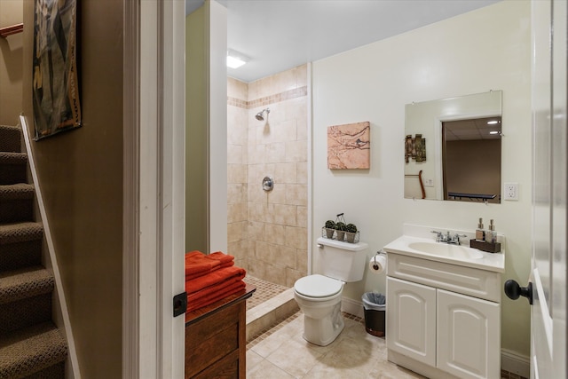 bathroom featuring a tile shower, vanity, toilet, and tile floors