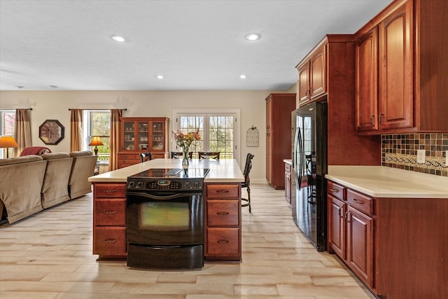 kitchen featuring a healthy amount of sunlight, light hardwood / wood-style floors, stainless steel fridge, and tasteful backsplash