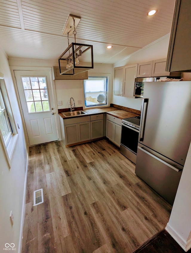 kitchen featuring pendant lighting, an inviting chandelier, sink, light hardwood / wood-style flooring, and appliances with stainless steel finishes