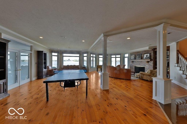 rec room featuring a stone fireplace, crown molding, and plenty of natural light