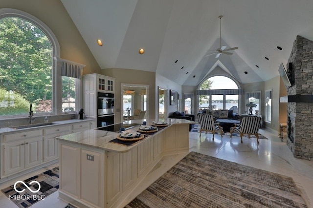 kitchen featuring a center island, high vaulted ceiling, light stone countertops, and light tile flooring