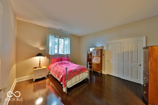 bedroom with dark hardwood / wood-style flooring and a closet