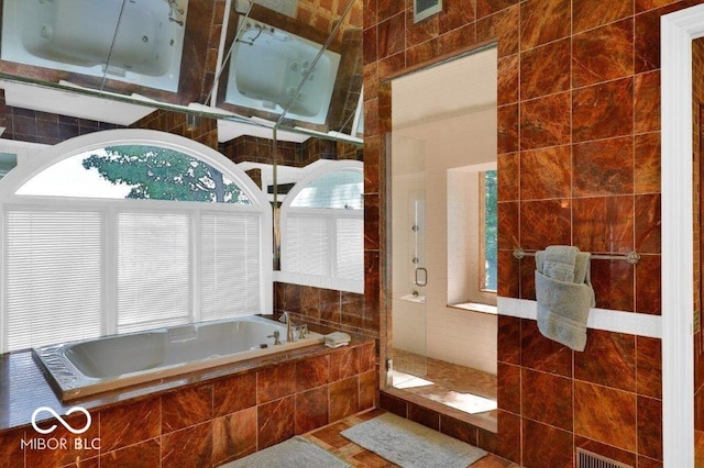 bathroom featuring tiled bath, plenty of natural light, tile walls, and tile flooring