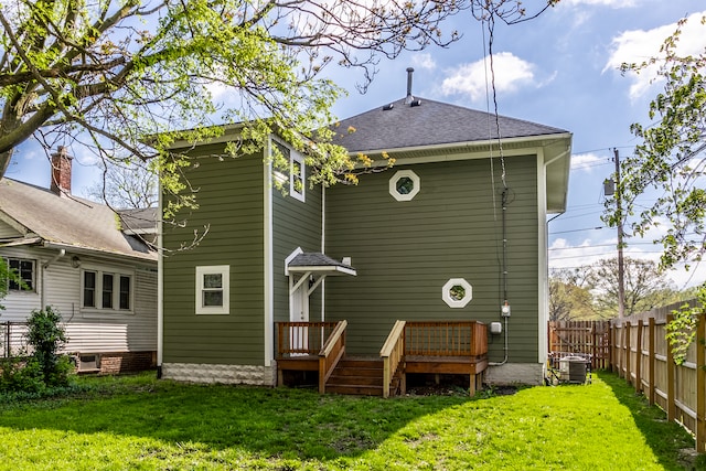 back of house with central air condition unit and a lawn