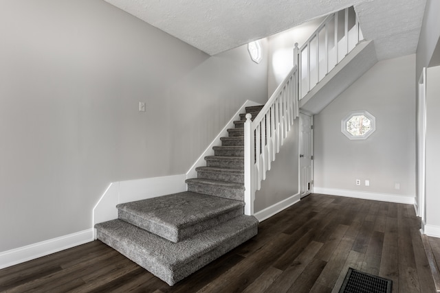 staircase with a textured ceiling and dark wood-type flooring