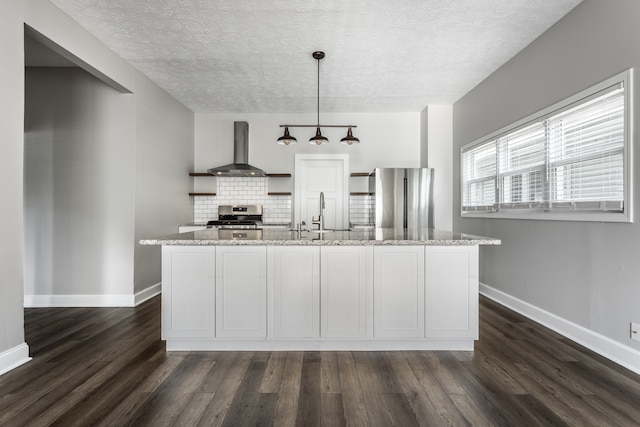 kitchen with appliances with stainless steel finishes, tasteful backsplash, wall chimney exhaust hood, and dark wood-type flooring