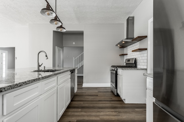 kitchen featuring appliances with stainless steel finishes, white cabinets, sink, wall chimney range hood, and tasteful backsplash