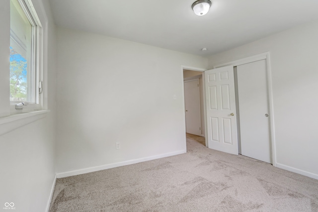 unfurnished bedroom with light colored carpet and a closet