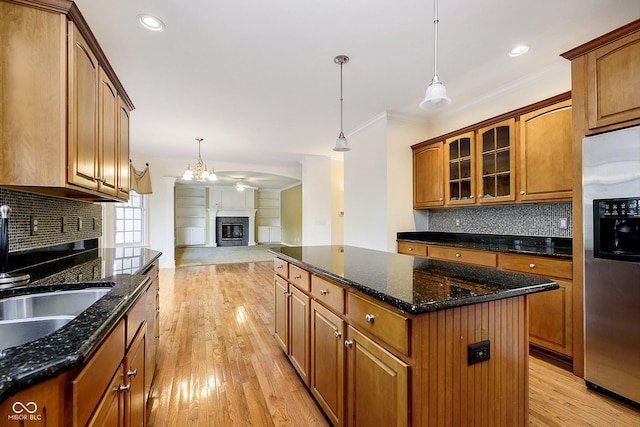 kitchen with stainless steel fridge, crown molding, decorative light fixtures, a center island, and light hardwood / wood-style floors