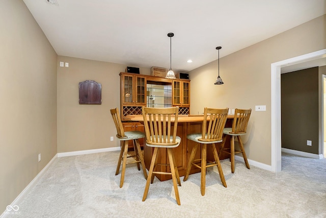 bar featuring built in fridge, hanging light fixtures, and light carpet