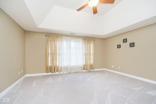 carpeted spare room with a tray ceiling and ceiling fan