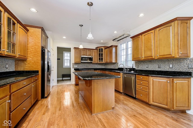 kitchen featuring stainless steel appliances, a kitchen island, a wealth of natural light, and light hardwood / wood-style floors