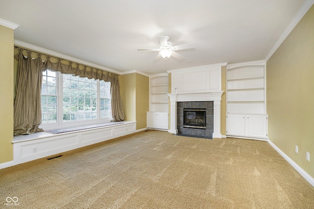 unfurnished living room with ceiling fan, built in features, crown molding, a fireplace, and carpet