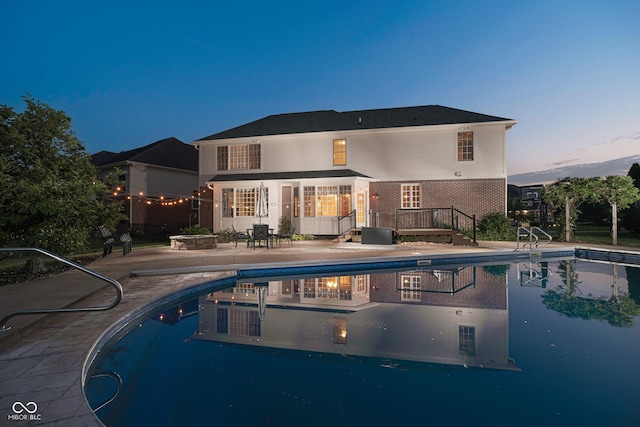 pool at dusk with a patio area