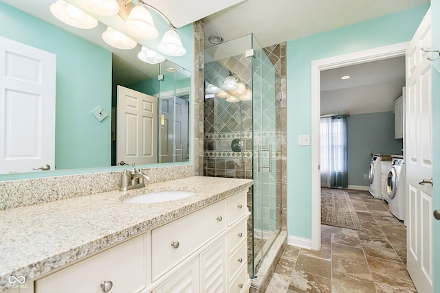 bathroom with a shower with door, vanity, and washer and dryer