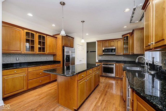 kitchen with light wood-type flooring, stainless steel appliances, sink, pendant lighting, and a kitchen island