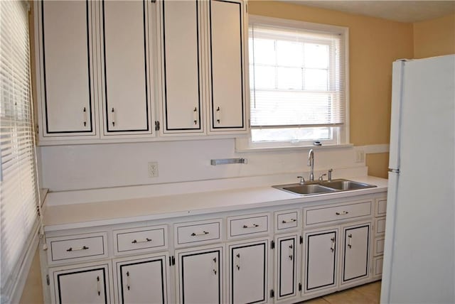 kitchen with white refrigerator, sink, a healthy amount of sunlight, and white cabinetry