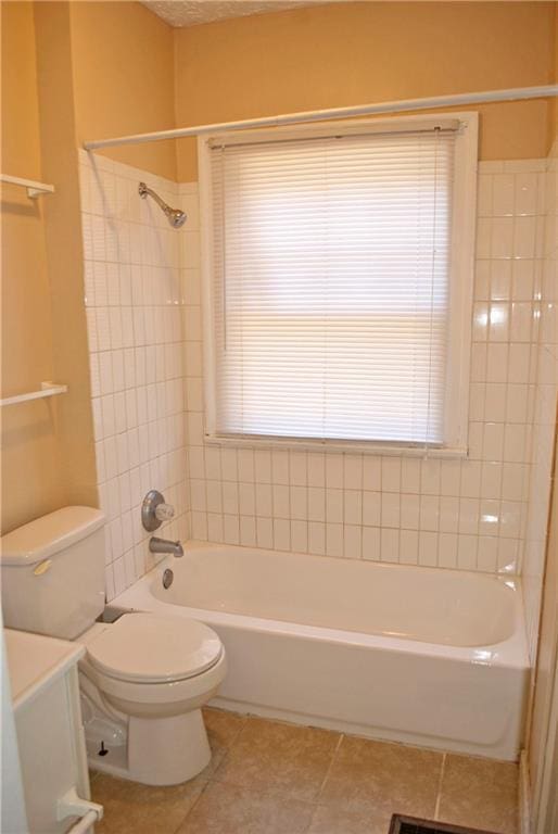 full bathroom featuring tiled shower / bath combo, plenty of natural light, tile floors, and toilet