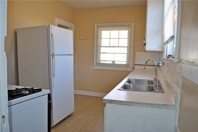 kitchen featuring sink, light tile flooring, white cabinetry, and white range with gas stovetop