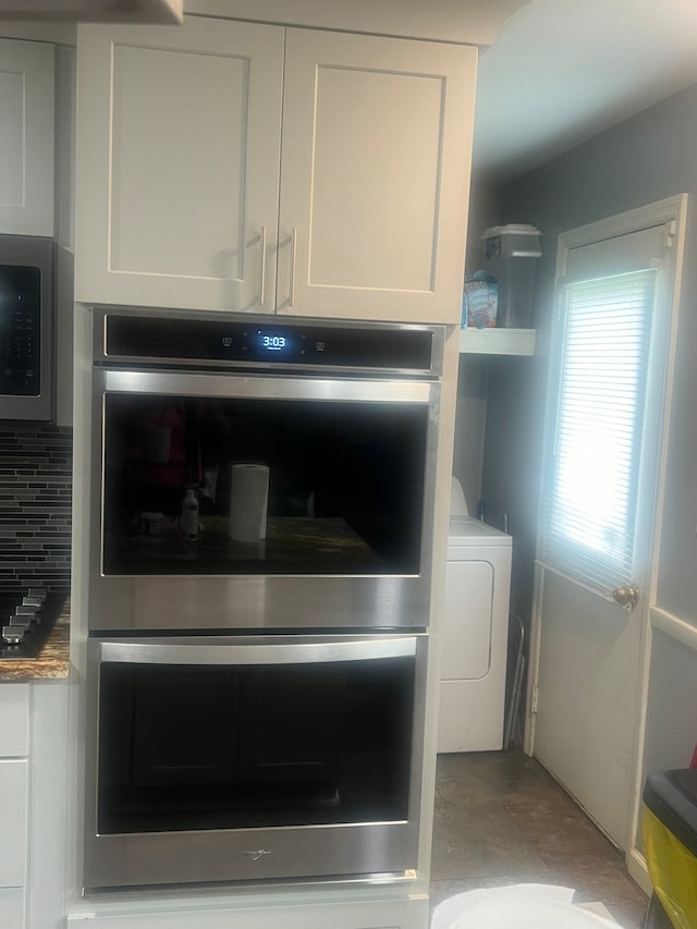 details featuring light tile floors, tasteful backsplash, black microwave, washer / dryer, and stainless steel double oven