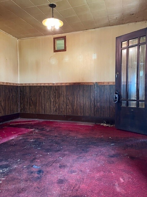 empty room featuring wooden walls and dark colored carpet