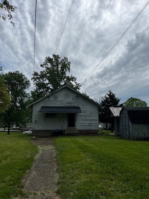 back of property featuring a lawn and a storage shed