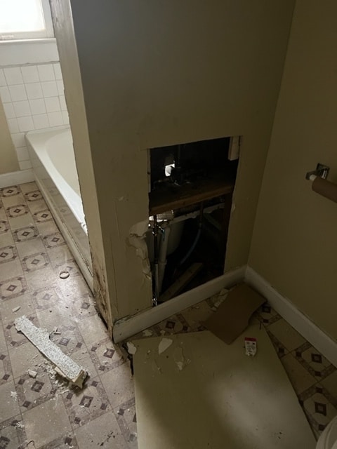 interior details featuring a bathing tub and light tile flooring