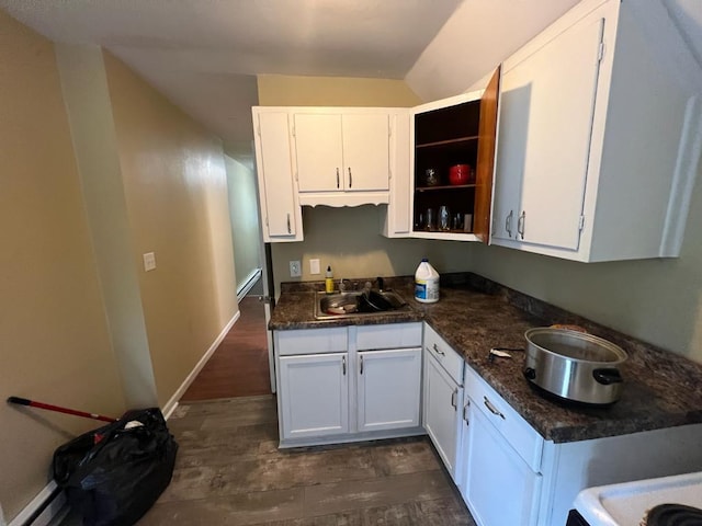 kitchen with sink, dark wood-type flooring, a baseboard heating unit, and white cabinetry