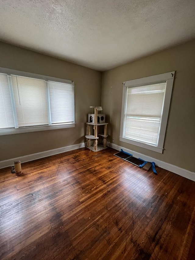 spare room with dark hardwood / wood-style floors and a textured ceiling