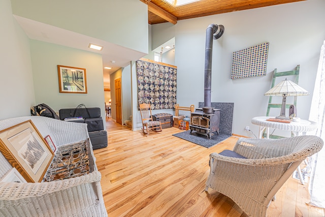 living room with wooden ceiling, beam ceiling, a wood stove, and hardwood / wood-style flooring