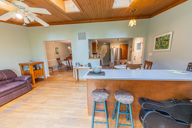 kitchen with ceiling fan, stainless steel fridge, a skylight, and wood ceiling