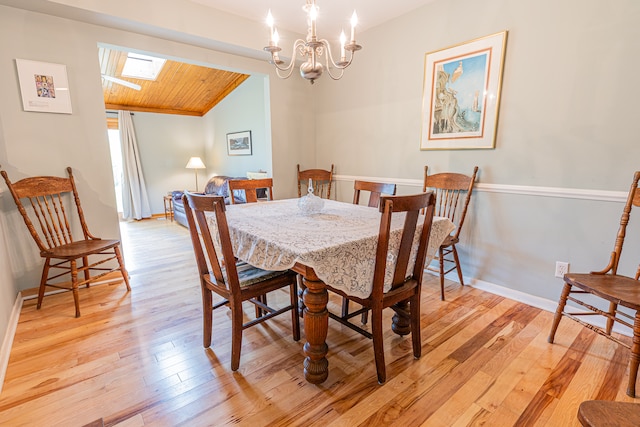 dining area with light wood-type flooring, an inviting chandelier, wood ceiling, and lofted ceiling with skylight