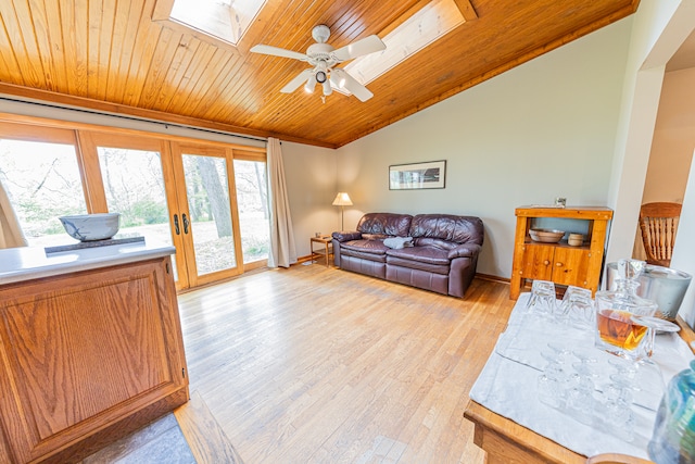 living room with wood ceiling, ceiling fan, french doors, lofted ceiling with skylight, and light hardwood / wood-style flooring