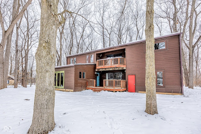 snow covered rear of property with a balcony and a deck