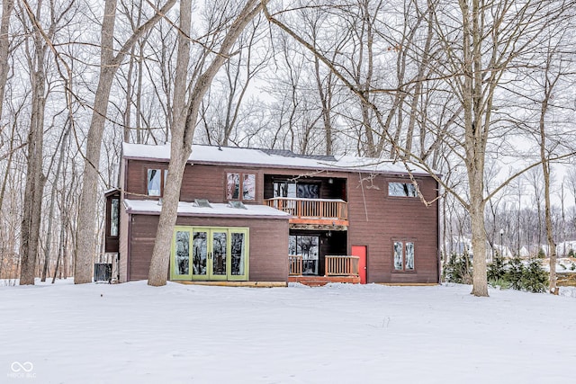 snow covered rear of property featuring a balcony