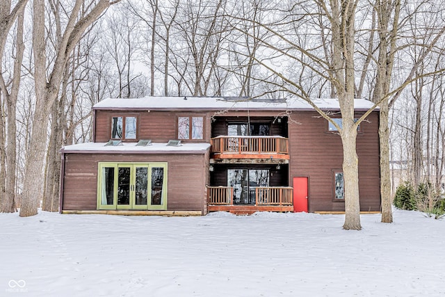 snow covered rear of property with a balcony