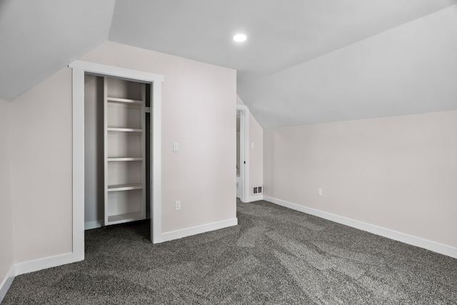 additional living space with dark colored carpet and lofted ceiling